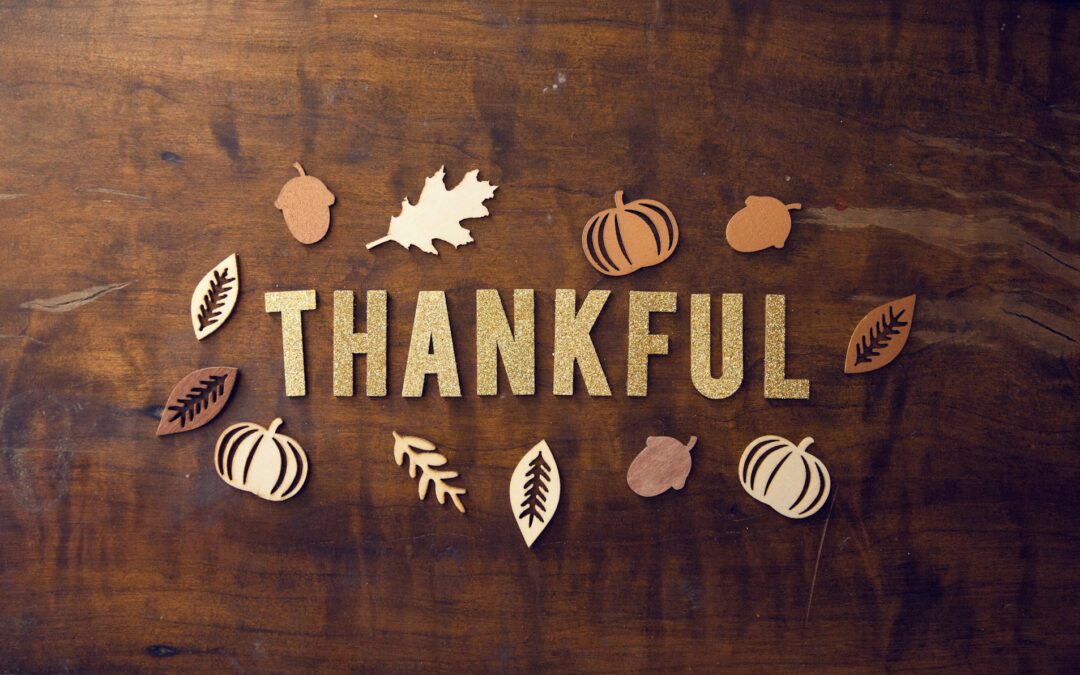 Glitter letters spelling out "Thankful" on a wood table